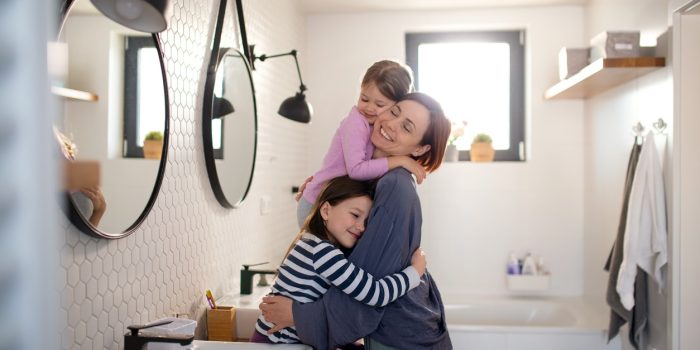 Mother Hugging Her Little Children In Safe And Clean Bathroom At Home