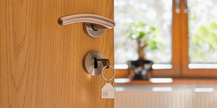 A Door Opening Up To A Vacation Home With A Key Shaped Like A House In The Lock.