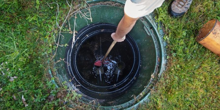 An Overhead Image Of Someone Cleaning Out A Septic Tank Surrounded By Grass.